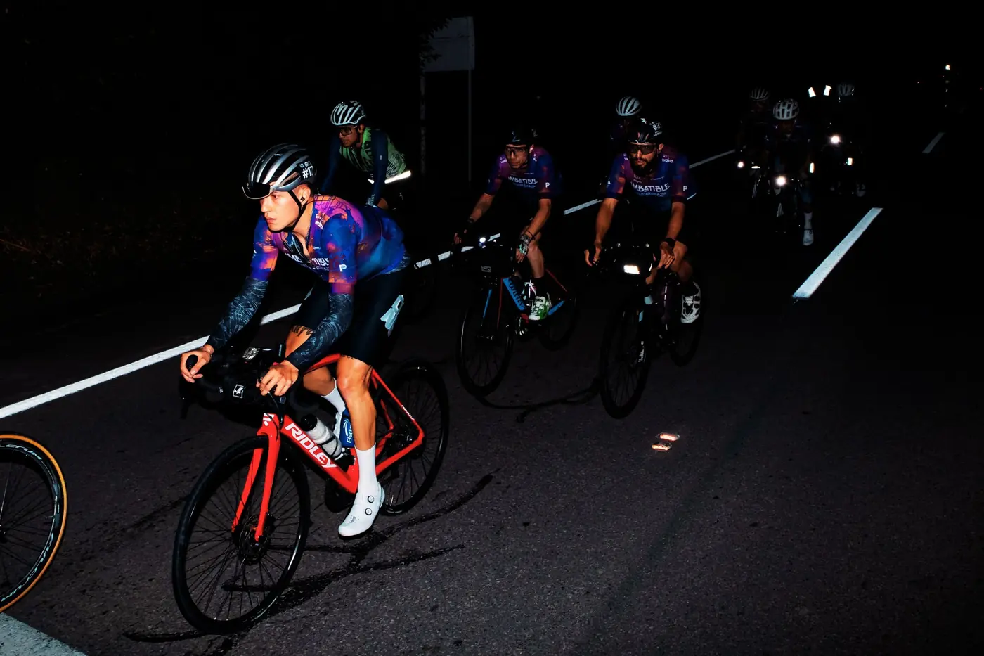 Ciclistas ascendiendo de noche con luces en la carretera